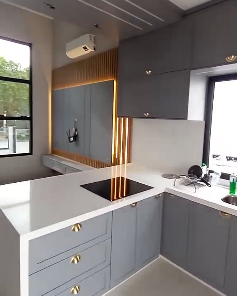 Cozinha cinza com bancada clara e puxadores dourados, no mesmo ambiente do painel