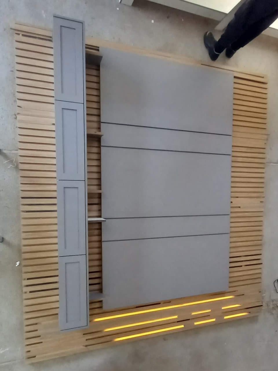 Painel de TV com moldura de ripado e fita de LED sendo montado na bancada da marcenaria